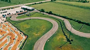 Circuito Wasaga 500 con campos abiertos, arbustos y un estacionamiento. 