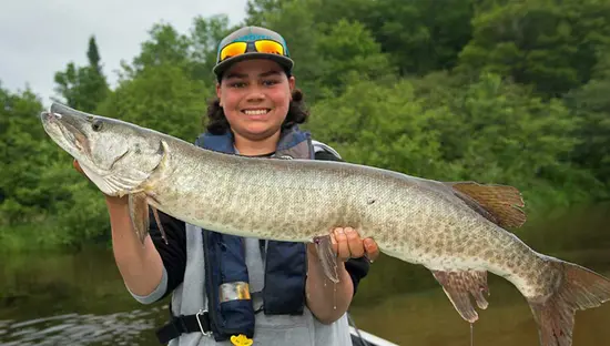 A young man in a boat holds a muskie caught in a back bay of Lake Huron's North channel.