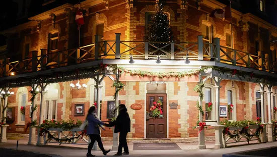 A couple holds hands in front of a romantic heritage inn in Niagara-on-the-Lake.