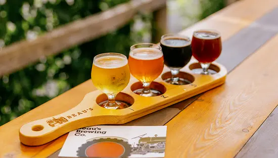 A selection of beers served with small dishes on a wooden tray.