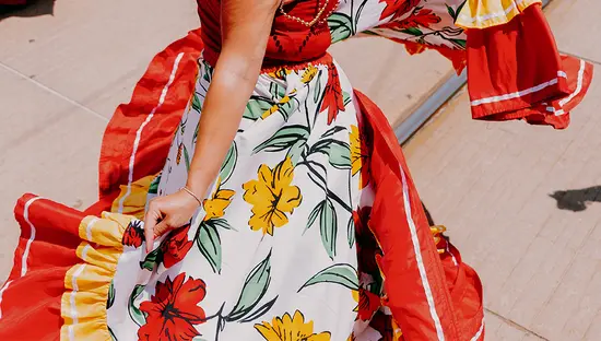 Una persona que lleva un vestido de flores con una falda de volantes roja y amarilla.