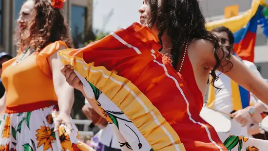 Women dressed in colourful orange and red print dance during the summer salsa festival in Toronto.