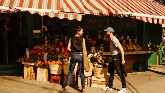 農産物のスタンドの前で会話する二人