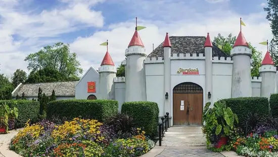 A white castle and large wooden doors at the entrance to a theme park.