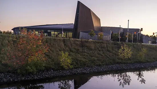 Evening photograph of the Canadian War Museum in front of the Ottawa River.