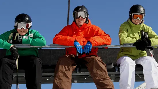 Three downhill skiers ride a ski lift at Mount. St. Louis Moonstone.