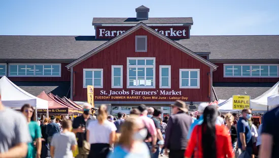 Eine Menschenmenge schlendert bei Tageslicht über den St. Jacobs Farmers' Market.