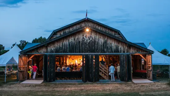 In einer umgebauten Scheune versammelt sich ein Publikum zu einer musikalischen Darbietung.