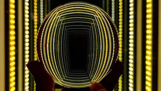 光を反射する地球儀を掲げる人の手。