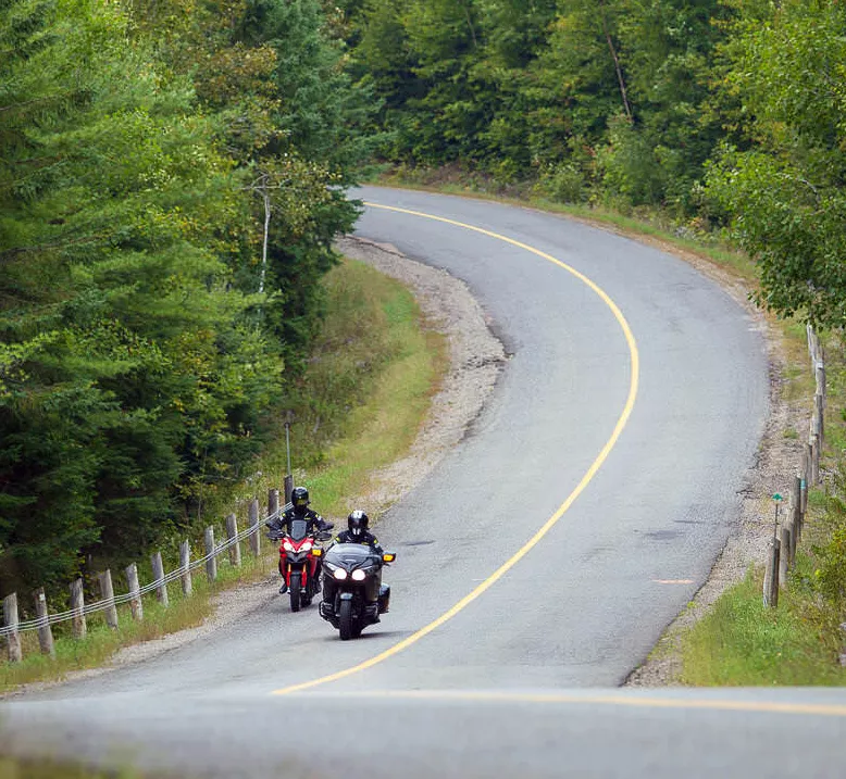 Two motorcyclists ride down a scenic highway.