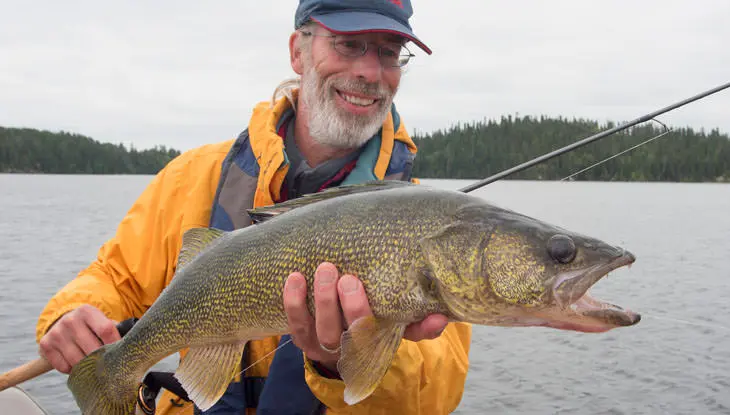 한 남자가 낚시 대회에서 잡은 큰 물고기를 들어 올리고 있다.
