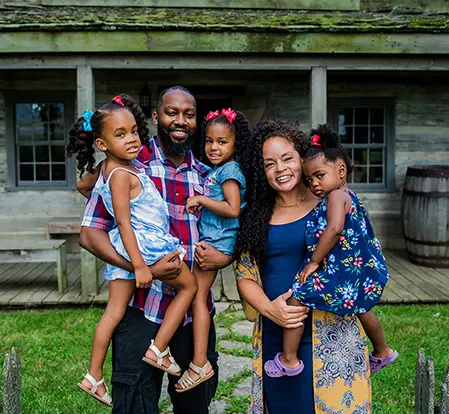 A family of five in front of a historic home