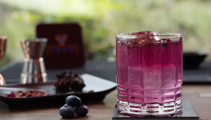 Une boisson avec de la glace sur une table à côté de quelques raisins.