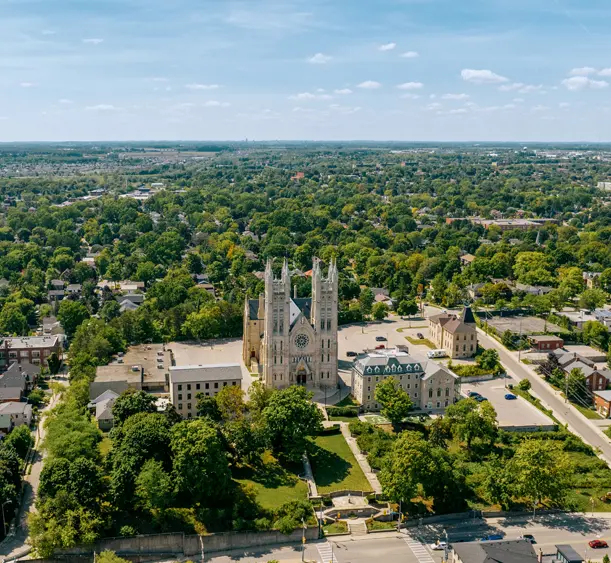 Luftaufnahme der Innenstadt von Guelph mit der Basilika Unserer Lieben Frau Immaculata mit ihren zwei Türmen, umgeben von baumgesäumten Straßen und der Stadtlandschaft.