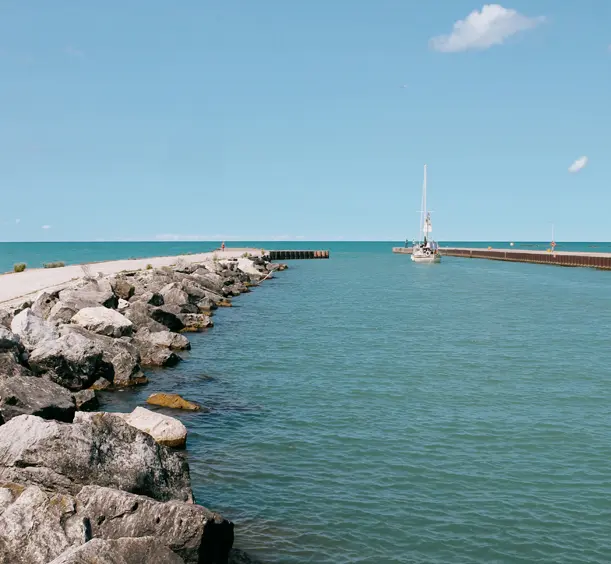 Steinerner Wellenbrecher und Pier, der sich ins türkisfarbene Wasser am Eingang zum Bayfield Harbour am Lake Huron erstreckt.