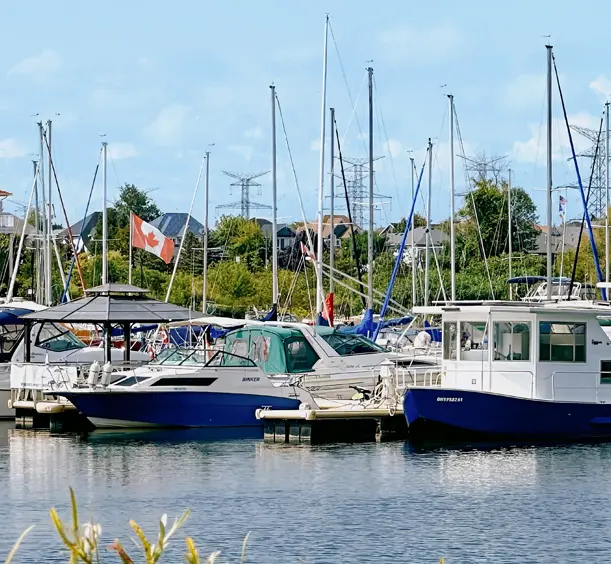 Des bateaux à la marina à Clarington, en Ontario, avec des mâts de voiliers au-dessus de l'eau et un drapeau canadien flottant dans l'air.