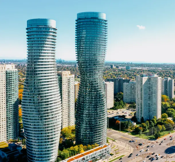 ミシサガのアブソリュート ワールド コンプレックスの航空写真。晴れた日に周囲の高層ビルの上にそびえ立つ、曲線を描くモダンなツインタワーが映えます。