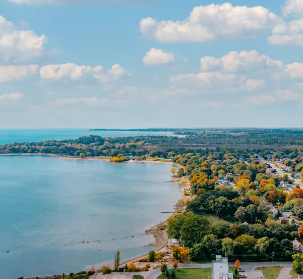 Aerial view of H.H. Knoll Lakeview Park and Lake Erie shoreline in Port Colborne, with colourful fall trees and a bright, cloud-filled sky.