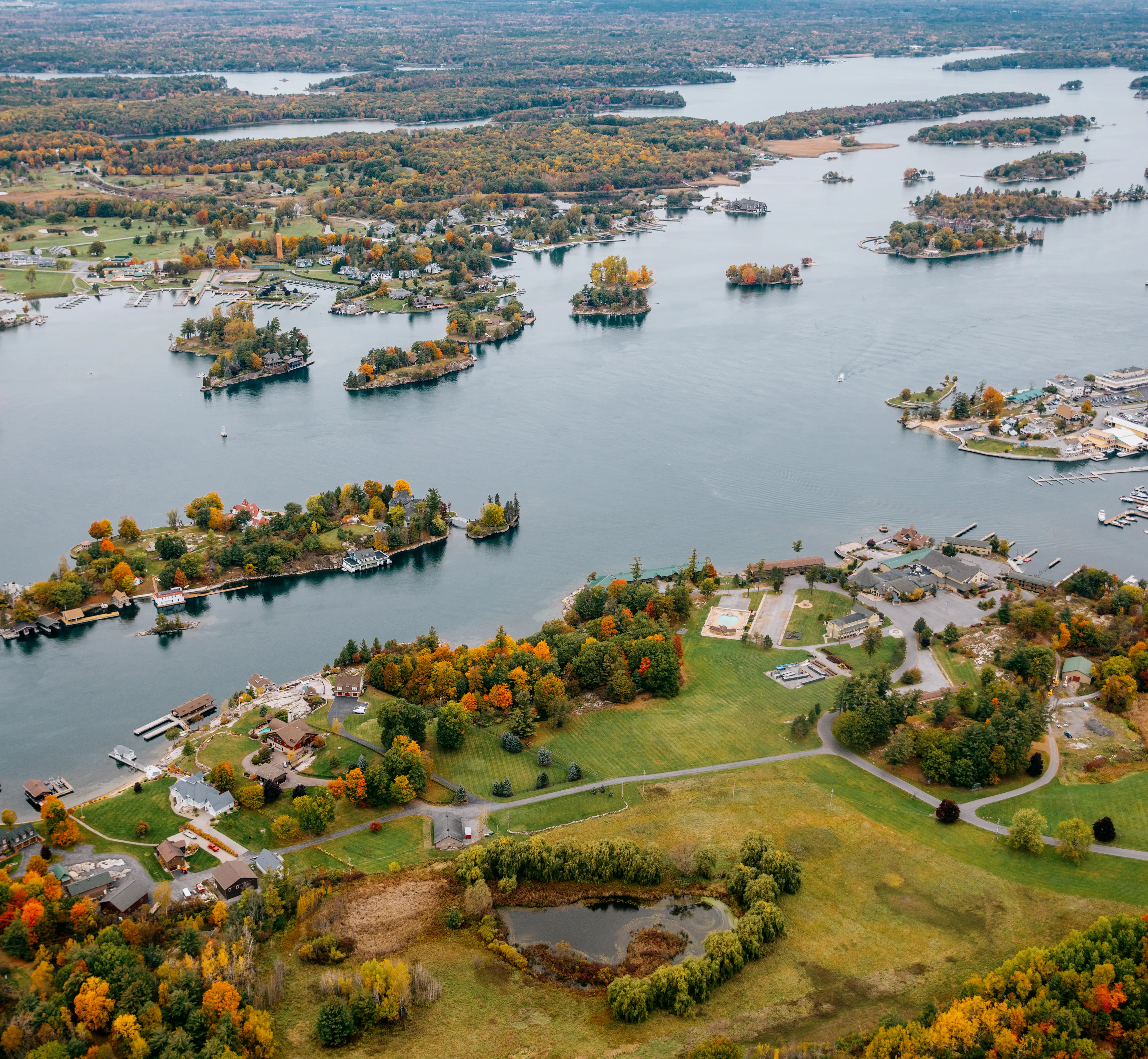 Luftaufnahme der Thousand Islands-Region mit ihren kleinen bewaldeten Inseln und Küstenhäusern an einem bewölkten Herbsttag.