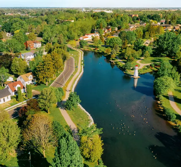 Aerial view of Wellington Park in Simcoe, with a winding river, green trees, and a white lighthouse-style structure in the water.