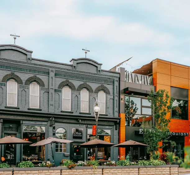 Historic downtown Kingsville streetscape on a sunny day, featuring heritage buildings with storefronts and leafy trees lining the street.