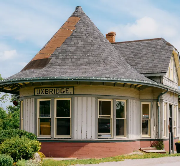 Gare historique d’Uxbridge, avec une tourelle, un parement crème et de grandes fenêtres, entourée de jardinières un jour d’été.