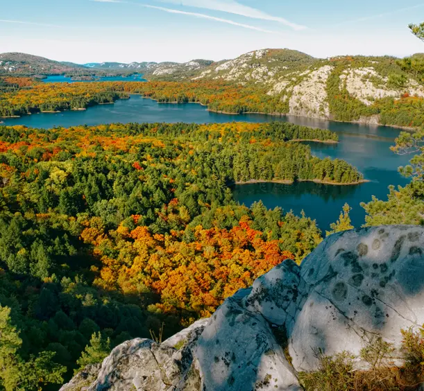 Malerische Aussicht auf den Killarney Provincial Park in Ontario mit leuchtendem Herbstlaub, das mehrere Seen und weiße Quarzitkämme umgibt.