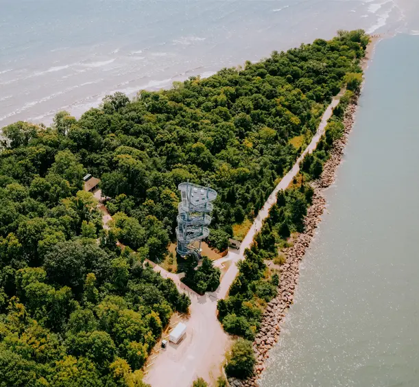 Boardwalk and spiral observation tower winding through lush forest at Point Pelee National Park in Leamington, Ontario, bordered by Lake Erie on both sides.