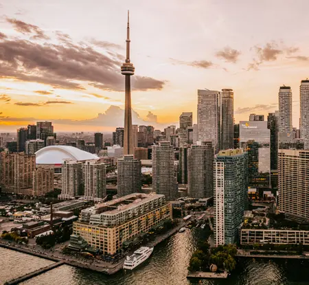 Cityscape view of Toronto from the harbour with the CN Tower and downtown standing against a dramatic sky.