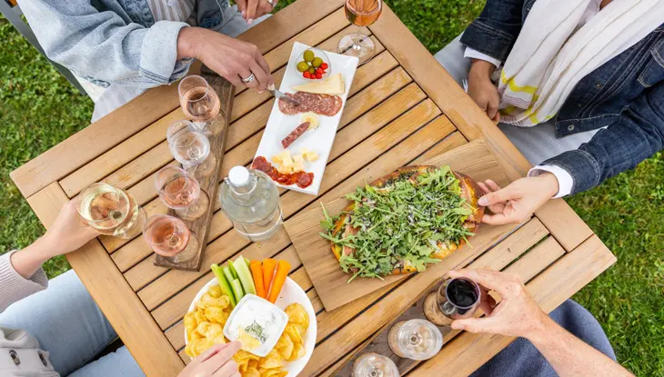 Four people enjoy wine tasting, charcuterie and snacks at a picnic table at Georgian Hills Vineyards near Blue Mountain.