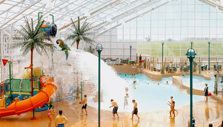 Indoor water park featuring a water slide and kids' splash zone with a giant tipping bucket at Americana Resort in Niagara Falls.