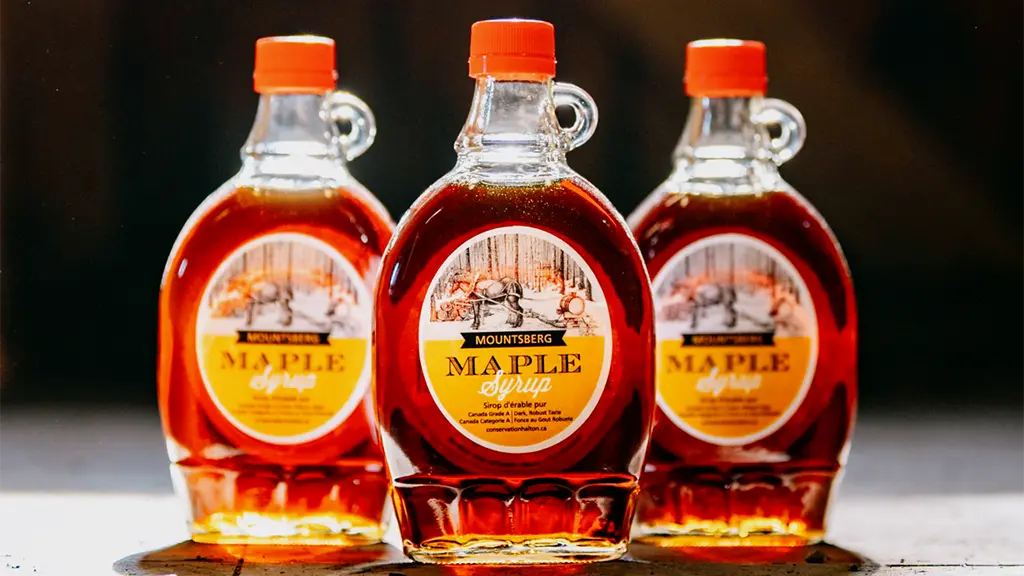 Trois bouteilles de sirop d'érable sont exposées.
