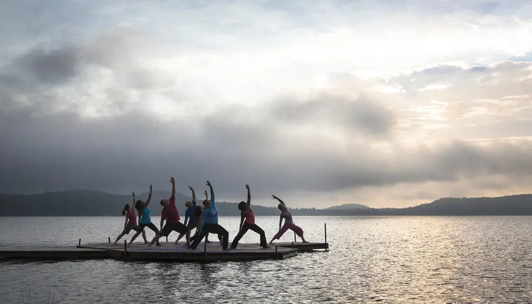 A group of people doing yoga on a wooden dock facing the lake in Northern Ontario.