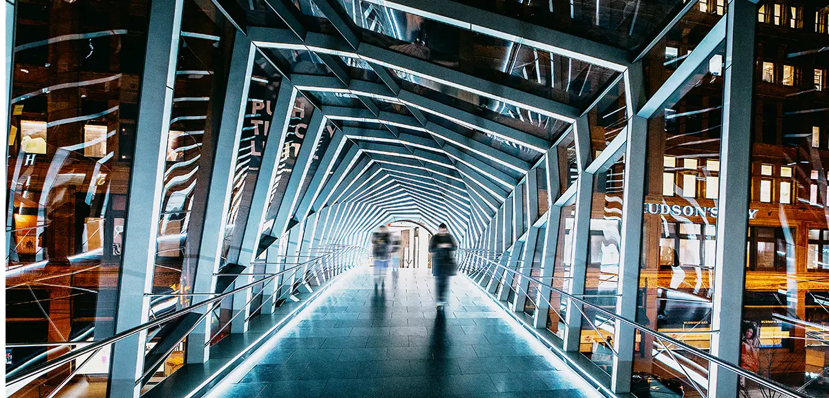 A futuristic illuminated walkway with glass walls and a geometric design in Toronto, glowing with white light.