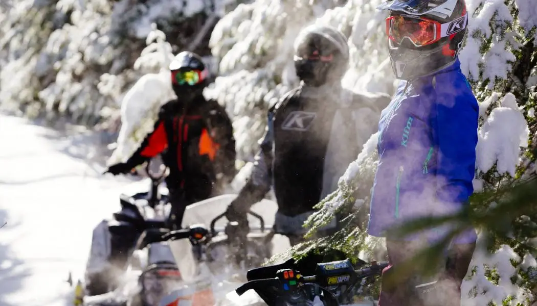Un grupo de tres conductores de motos de nieve se toma un descanso de andar en moto por un sendero OFSC cerca de Timmins.