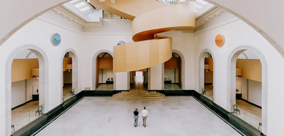 Atrium spacieux d’un musée avec des balcons incurvés et des visiteurs qui marchent dans un espace ouvert.
