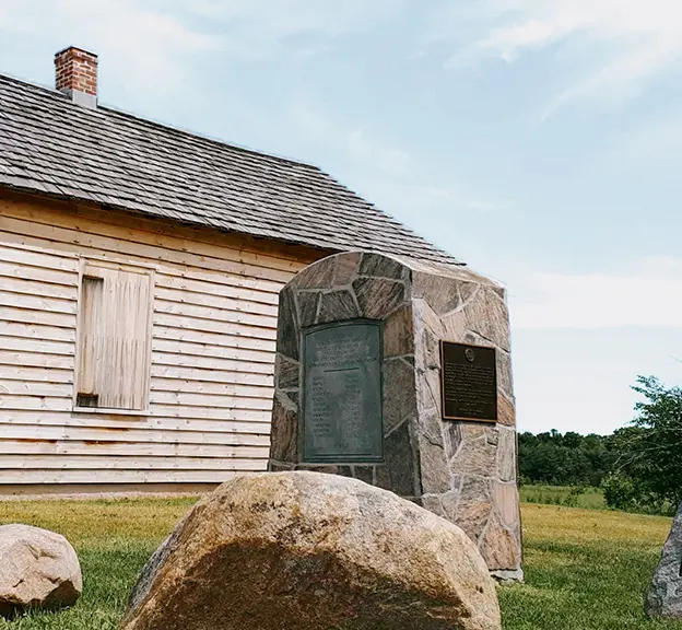 芝生の敷地に建つ、石の標識や記念碑に囲まれた、歴史ある小さな木造教会。芝生の敷地に建つ、石の標識や記念碑に囲まれた、歴史ある小さな木造教会。