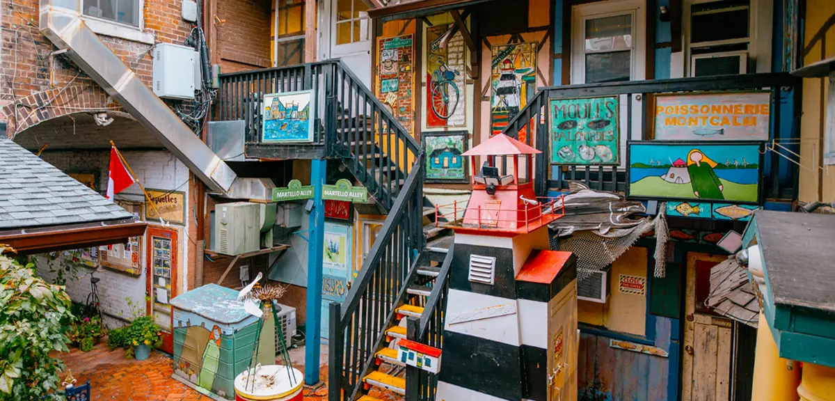 Ein mit farbenfrohen Wandmalereien, Skulpturen und Kunstinstallationen geschmückter Innenhof, umgeben von Backsteingebäuden.