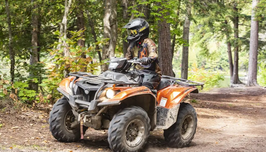  Une personne portant une tenue de camouflage et un casque conduit un VTT sur un chemin de terre dans le nord-est de l'Ontario.