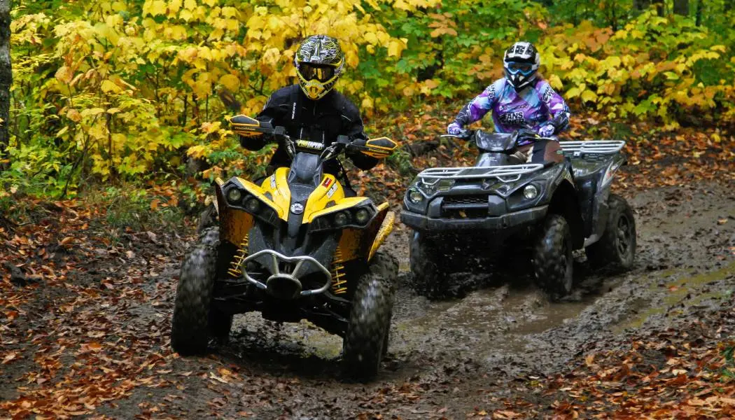 물가의 지형을 주행하는 두 대의 ATV.