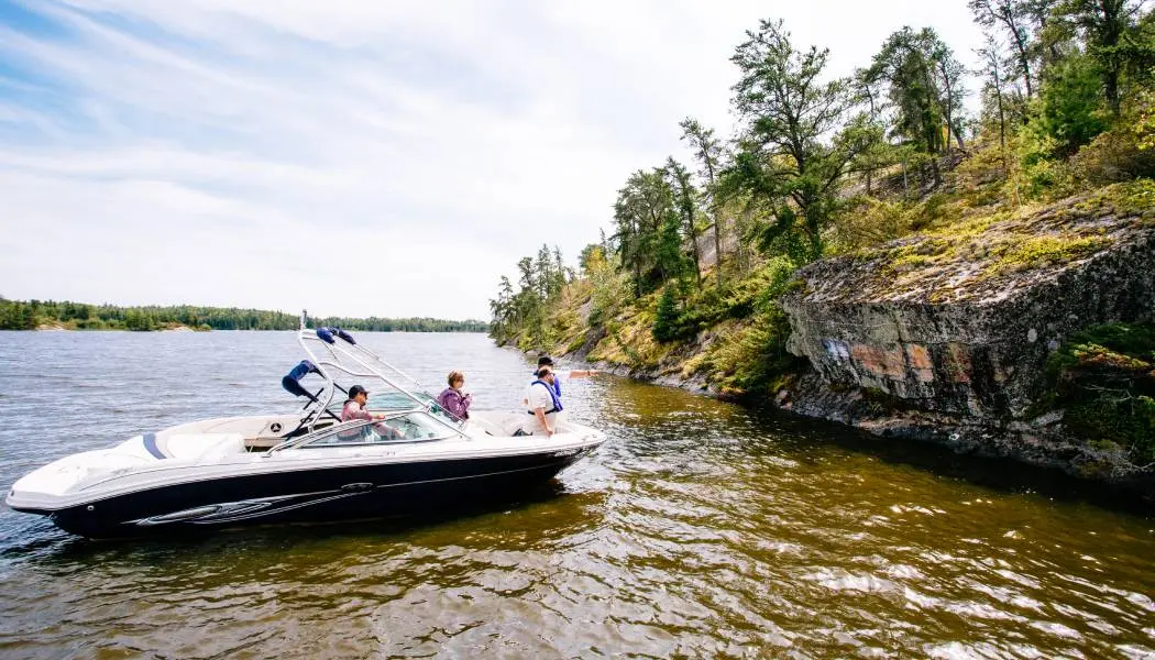 Cuatro personas a bordo de una lancha motora admiran las singulares formaciones rocosas que bordean la costa del lago de los Bosques.