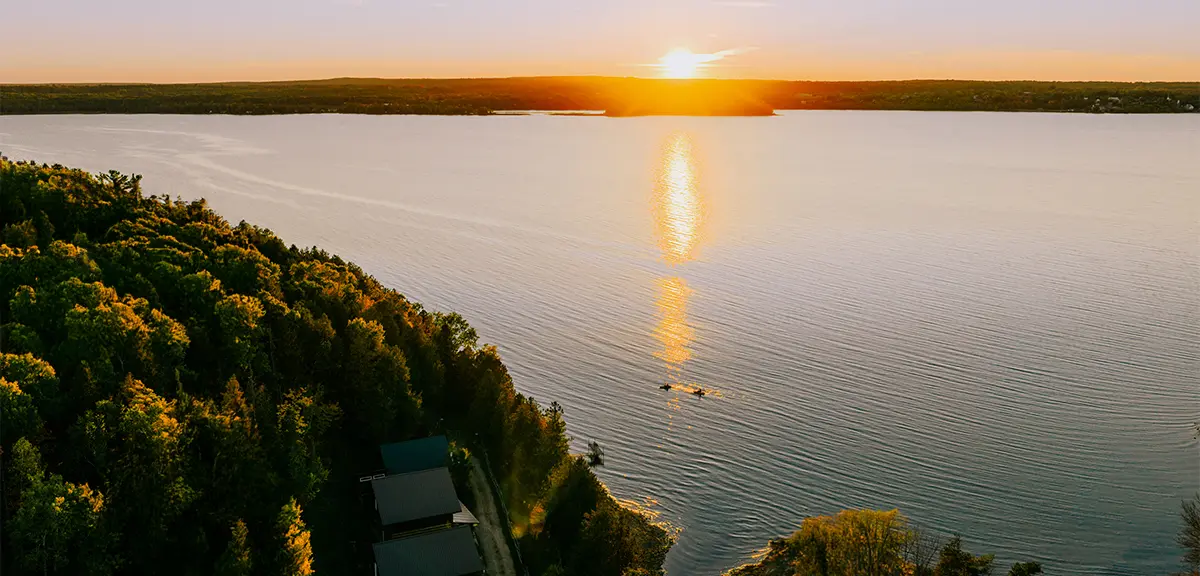 Vue aérienne d’un coucher de soleil sur un lac bordé d’une forêt.