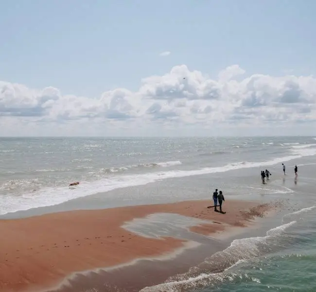 Un hombre empuja a una mujer en un columpio en la orilla de arena de una playa con vistas al lago Erie.