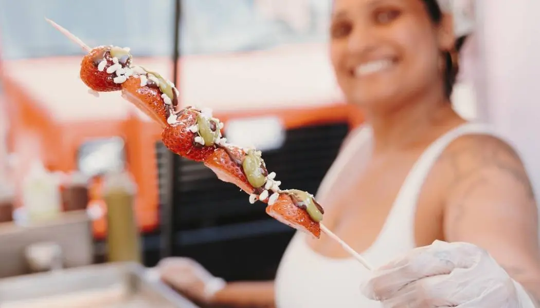 Un pastel, un sándwich, bebidas y otros alimentos para picnic sobre una manta a cuadros rojos del Savour and Sip Trail en Stratford, Ontario.
