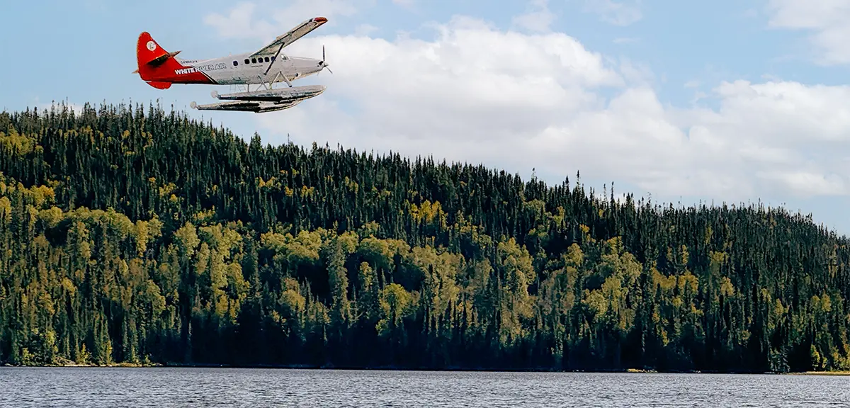 Ein Wasserflugzeug, das über einen See und einen ausgedehnten Wald fliegt, bringt Jäger zu einem abgelegenen Jagdposten im Norden Ontarios.