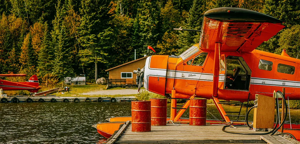  森に囲まれた湖の木製桟橋に水上飛行機が駐機している。