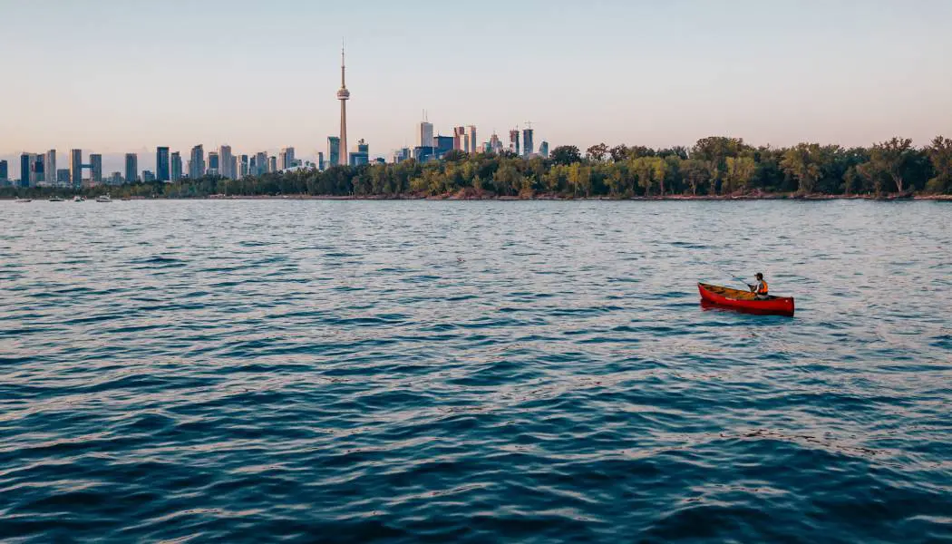 Ein Mann warf in einem Kanu im Hafen von Toronto seine Angel aus; im Hintergrund waren der CN Tower und die Skyline der Stadt zu sehen.