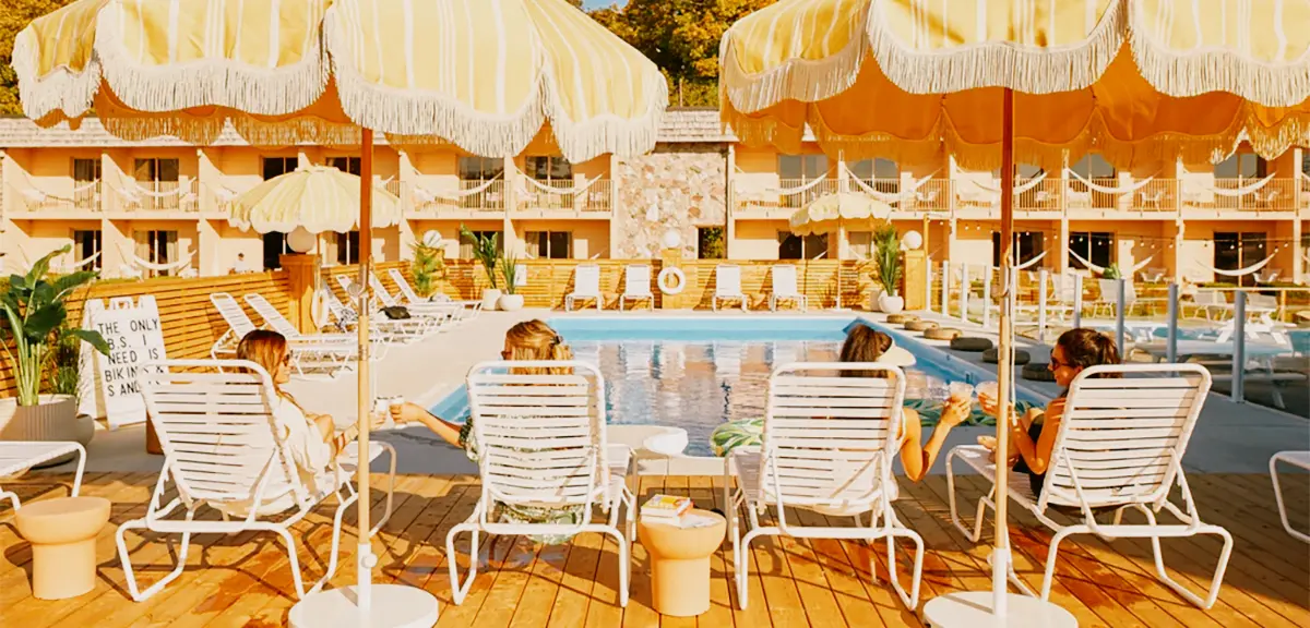 Los huéspedes se relajan en tumbonas bajo sombrillas a rayas junto a la piscina del June Motel en el condado de Prince Edward.