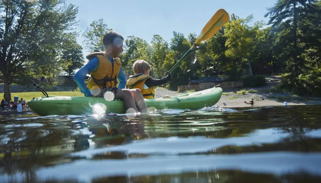 Zwei kleine Jungen vergnügen sich beim Kajakfahren und Spielen auf dem See an einem klaren Sommertag.