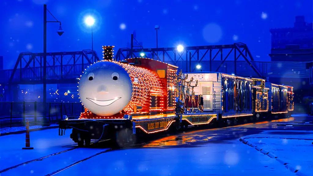 A train with a smiling face at its front is decorated and lit up at night for the holidays.